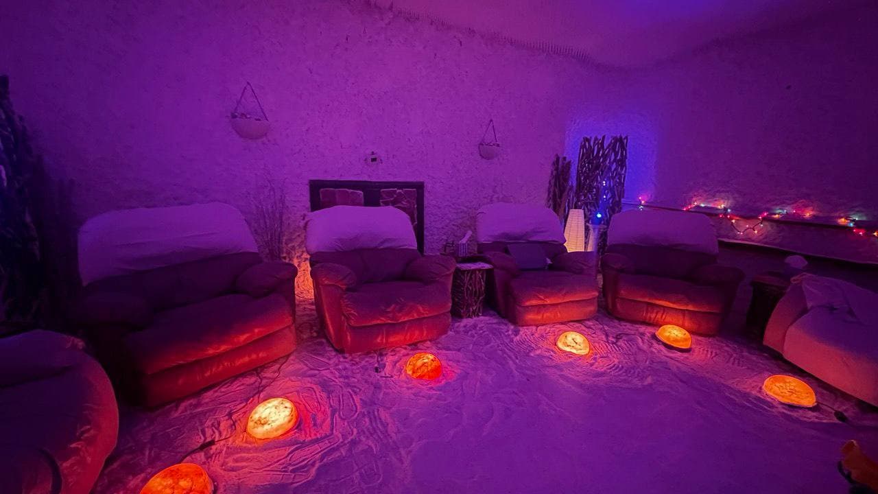 Recliners and glowing salt lamps inside the Himalayan salt room at Salinair